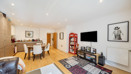 Open-plan living and kitchen area with television, sofas, and dining table.