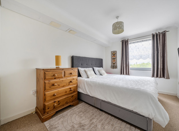 Bedroom with double bed, chest of drawers, and window.