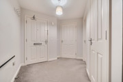 Hallway with multiple doors, radiator and carpeted flooring.