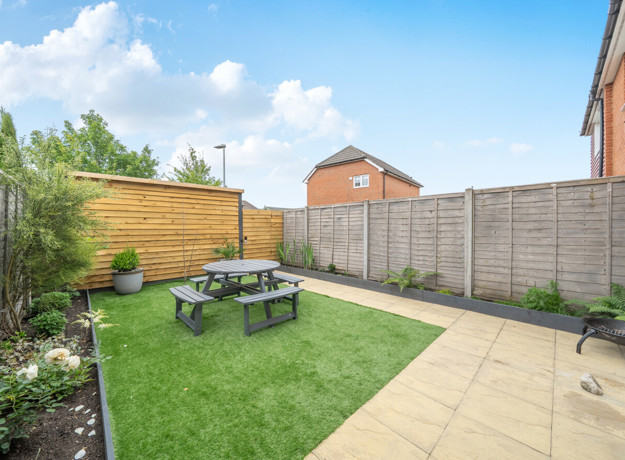 Garden with lawn, patio seating area and fenced boundary.