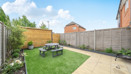 Garden with lawn, patio seating area and fenced boundary.