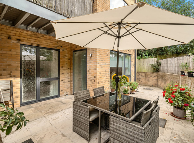 Patio with outdoor seating, parasol and potted plants.