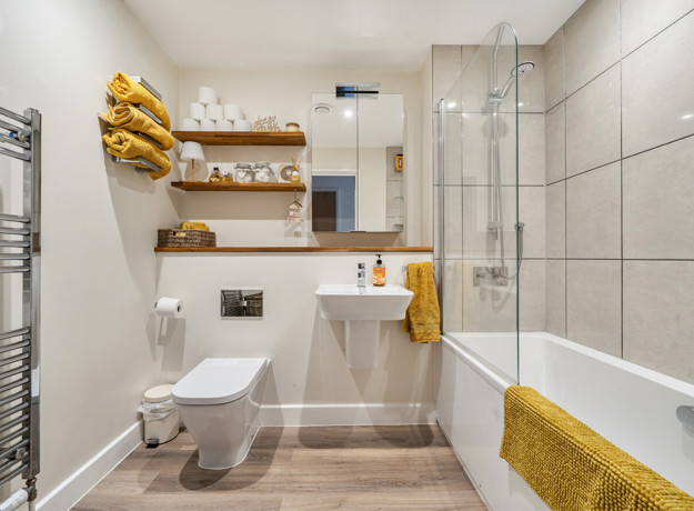 Bathroom with a bathtub, shower enclosure, toilet and wall-mounted shelves.
