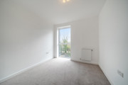 Carpeted bedroom with white walls, radiator, and large window