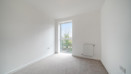Carpeted bedroom with white walls, radiator, and large window