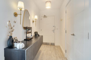 Hallway with console table, round mirror, doors and built-in storage.