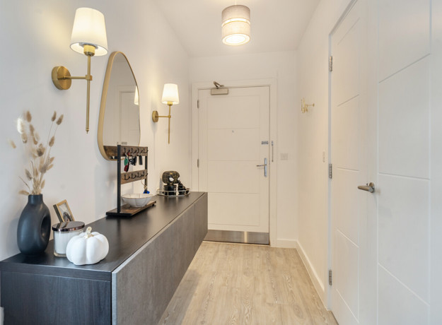 Hallway with console table, round mirror, doors and built-in storage.