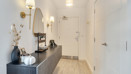 Hallway with console table, round mirror, doors and built-in storage.