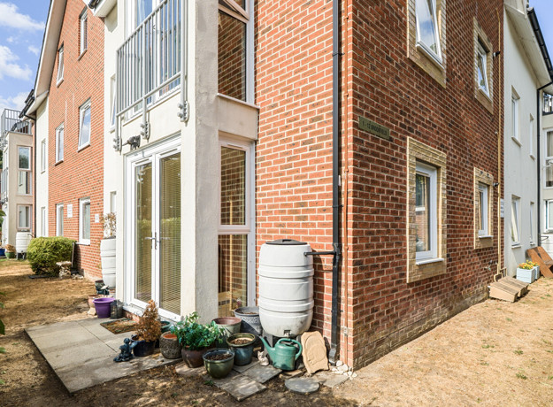 Exterior corner view of a brick apartment building with pathways.