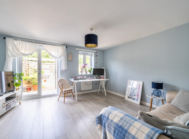 Living room with sofas, dining table, and patio doors to the garden.