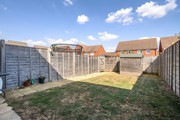 Enclosed rear garden with lawn, paved path, shed and wooden fencing.