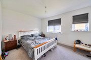 Bedroom with double bed, bedside tables, and two windows with blinds.