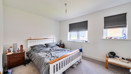 Bedroom with double bed, bedside tables, and two windows with blinds.