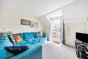 Living room with blue corner sofa and doors leading to a balcony.