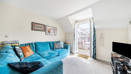 Living room with blue corner sofa and doors leading to a balcony.