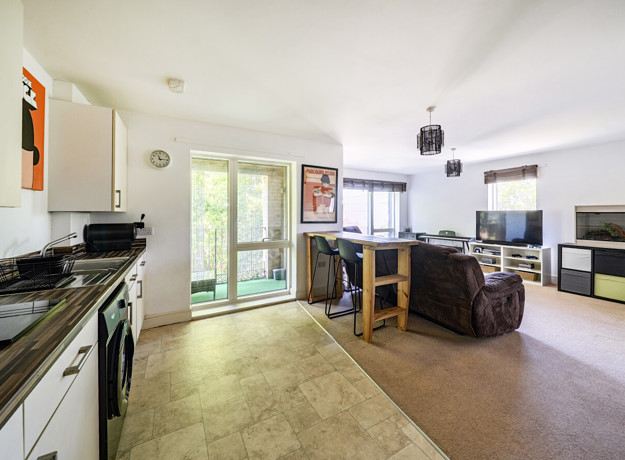 Open-plan kitchen and living area with glass doors to a balcony.