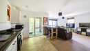 Open-plan kitchen and living area with glass doors to a balcony.