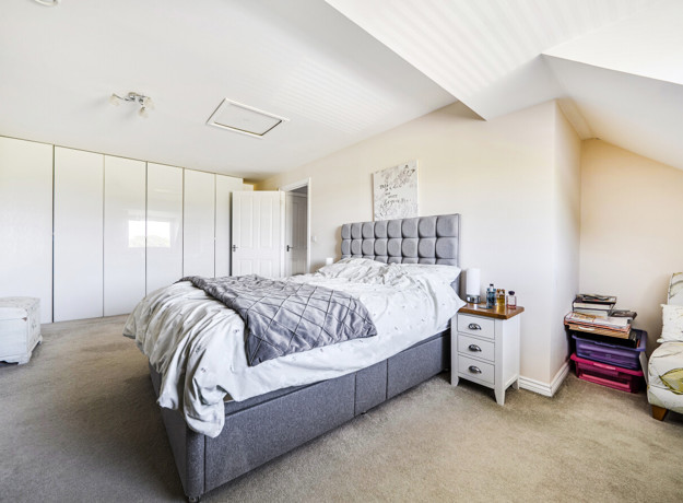 Spacious bedroom with double bed, sloped ceiling and fitted wardrobes