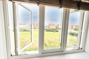View from a window overlooking grass field, playground and houses in the distance.