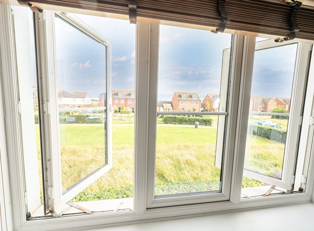 View from a window overlooking grass field, playground and houses in the distance.