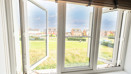 View from a window overlooking grass field, playground and houses in the distance.