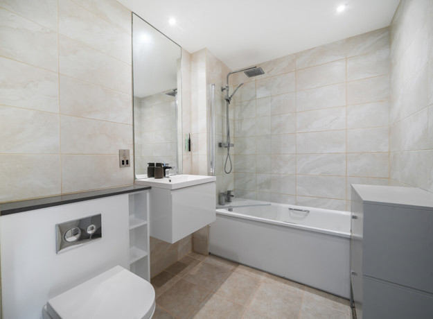 Bathroom with a bathtub, shower screen, vanity unit and toilet.