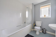 Bathroom with bathtub, toilet, sink, and frosted window .