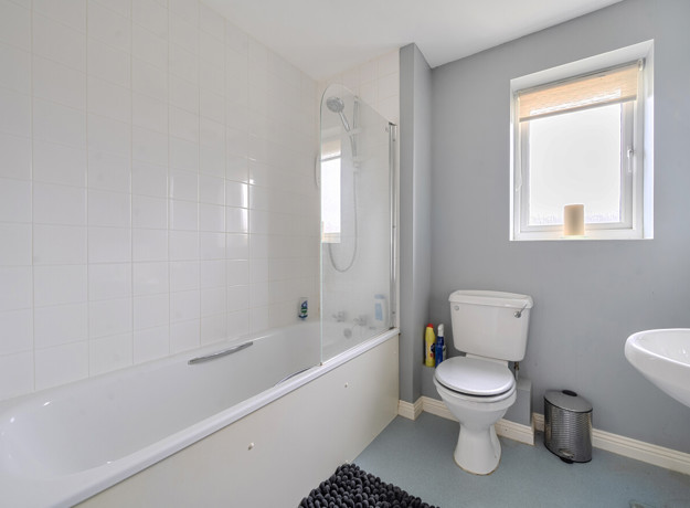 Bathroom with bathtub, toilet, sink, and frosted window .