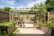 Garden with pergola, gravel area, raised beds, and fencing.