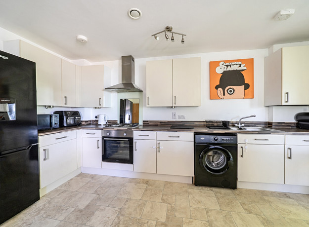 Kitchen with white cabinets, appliances, and a washing machine.