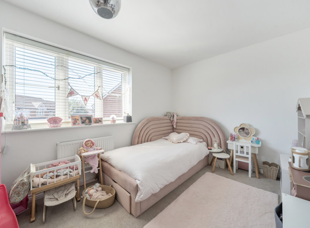 Child's bedroom with a bed, window, rug and toys.
