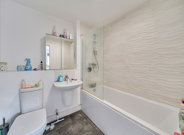 Bathroom with bathtub, shower screen, toilet, and sink.