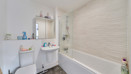 Bathroom with bathtub, shower screen, toilet, and sink.
