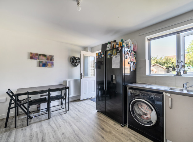 Dining and kitchen area with table, appliances, window and door into garden.