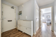 Hallway with wooden-effect floor, radiator, cabinet and view into another room.