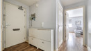 Hallway with wooden-effect floor, radiator, cabinet and view into another room.