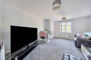 Living room with sofa, TV, glass dining table with chairs, carpeted floor and window