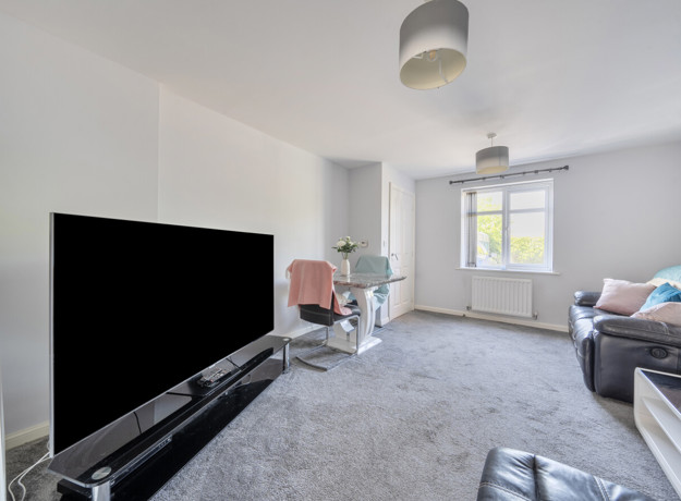 Living room with sofa, TV, glass dining table with chairs, carpeted floor and window