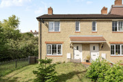 Two storey end-of-terrace brick house with front garden, path and white door.