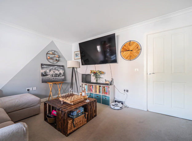 Bright living room with sofa, TV, storage chest and white walls