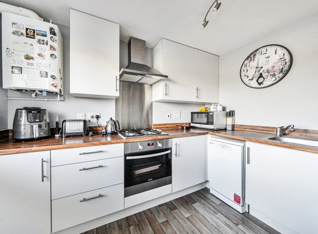 Modern kitchen with white cabinets, wooden-effect worktops, backsplash and appliances