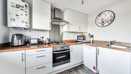 Modern kitchen with white cabinets, wooden-effect worktops, backsplash and appliances