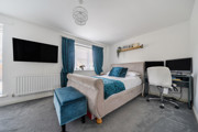 Bedroom with double bed, desk, wall-mounted TV and blue curtains.