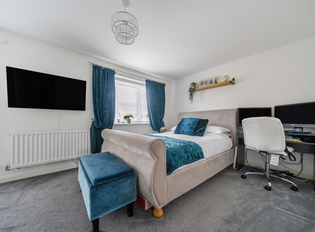 Bedroom with double bed, desk, wall-mounted TV and blue curtains.