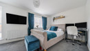 Bedroom with double bed, desk, wall-mounted TV and blue curtains.