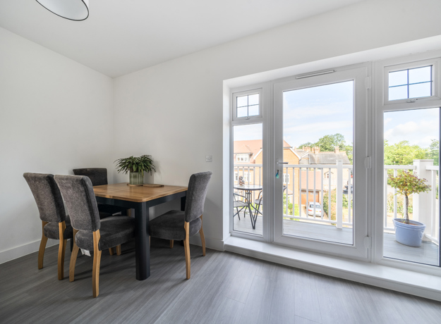 Dining area with table and chairs beside glass doors leading to balcony.