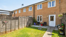 Rear garden with a lawn, fenced boundaries and the back of a brick house.