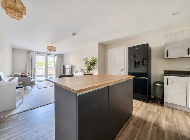 Open-plan kitchen and living area with island unit and seating.