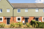 Row of terraced houses with front gardens and paved walkway.