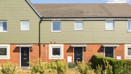 Row of terraced houses with front gardens and paved walkway.